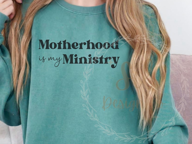 May include: A teal sweatshirt with the text "Motherhood is my Ministry" printed in black.