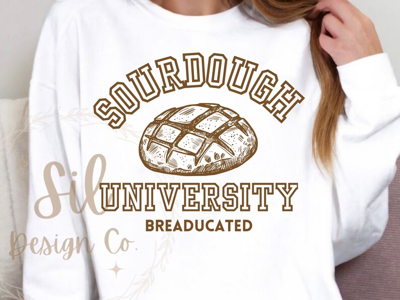 May include: White sweatshirt with brown text that reads "Sourdough University Breadeducated" and a drawing of a sourdough loaf of bread.