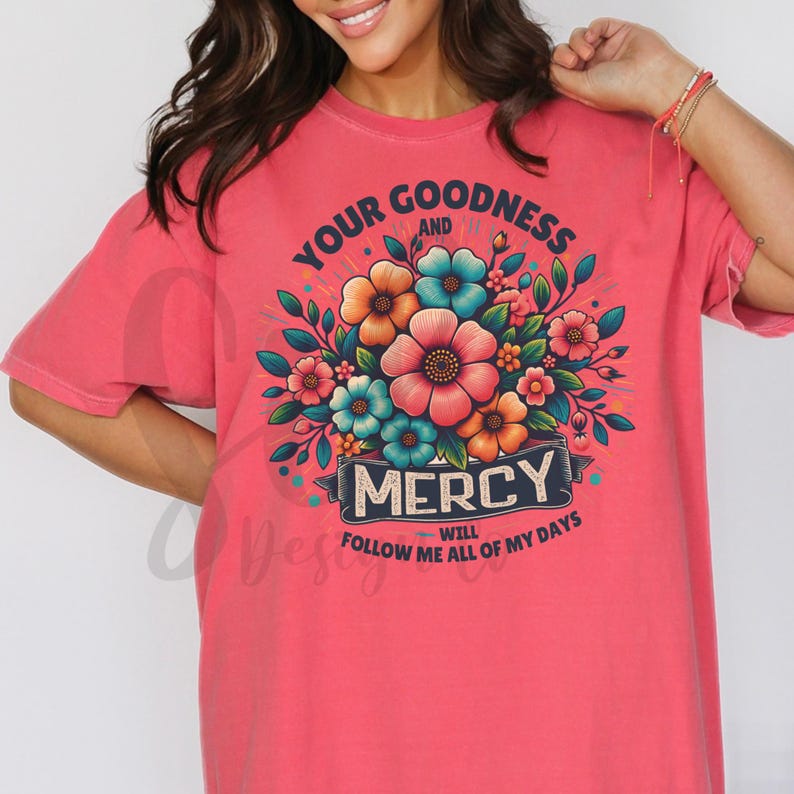 Puede incluir: Una camiseta rosa con un dise&ntilde;o floral y el texto "Your Goodness and Mercy Will Follow Me All of My Days".