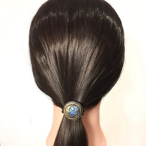 May include: A black hair tie with a blue and gold crescent moon and stars design.