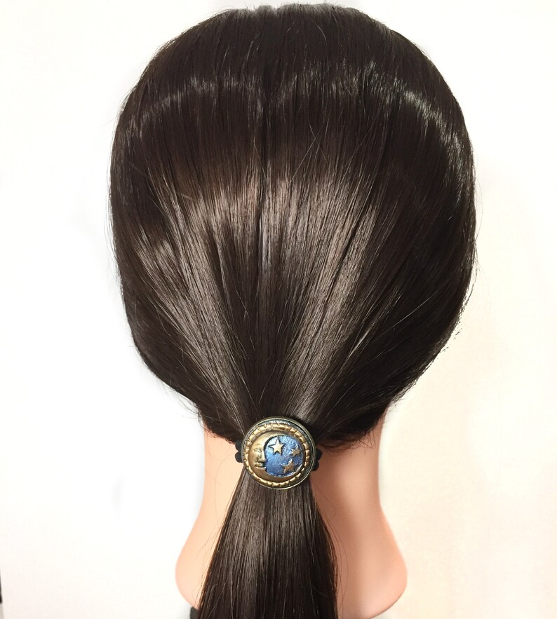 May include: A black hair tie with a blue and gold crescent moon and stars design.