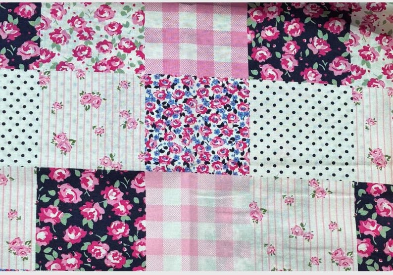 May include: A patchwork fabric with a variety of patterns. The design includes squares of pink gingham, white polka dots, pink roses on navy, and floral prints with pink and blue flowers. The overall theme is a vintage, floral design.
