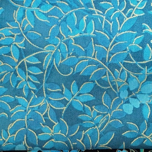 May include: Close-up of a teal fabric with a repeating pattern of stylized leaves and vines. The leaves are in shades of teal and blue, with gold-colored veins and stems. The fabric has a textured appearance.