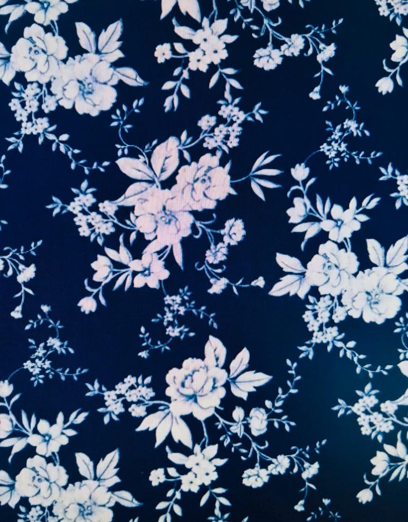 May include: Dark navy blue fabric with a repeating floral pattern. The design features white and light blue flowers of various sizes, including roses and smaller blossoms, with delicate stems and leaves.