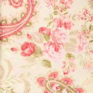 May include: A floral fabric featuring a cream background with a pattern of pink roses, smaller pink flowers, and green leaves. The design includes paisley-like shapes in pink and green, creating a vintage, romantic aesthetic.