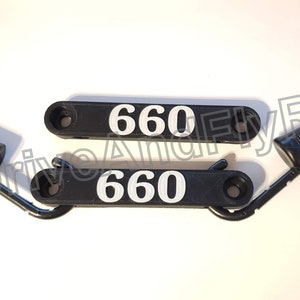 Puede incluir: Dos ganchos de pl&aacute;stico negro con el n&uacute;mero "660" impreso en blanco en cada uno. Los ganchos tienen un bucle de metal en un extremo y un peque&ntilde;o agujero en el otro extremo.