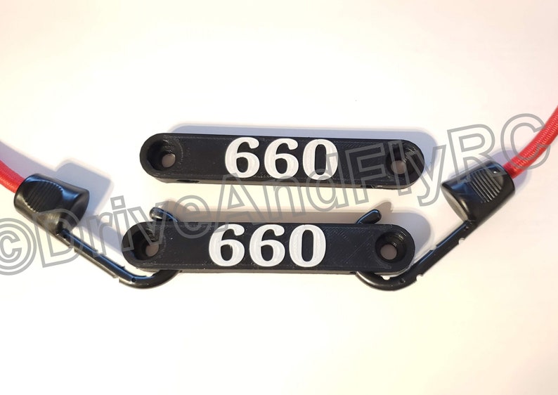 Puede incluir: Dos ganchos de pl&aacute;stico negro con el n&uacute;mero "660" impreso en blanco en cada uno. Los ganchos tienen un bucle de metal en un extremo y un peque&ntilde;o agujero en el otro extremo.