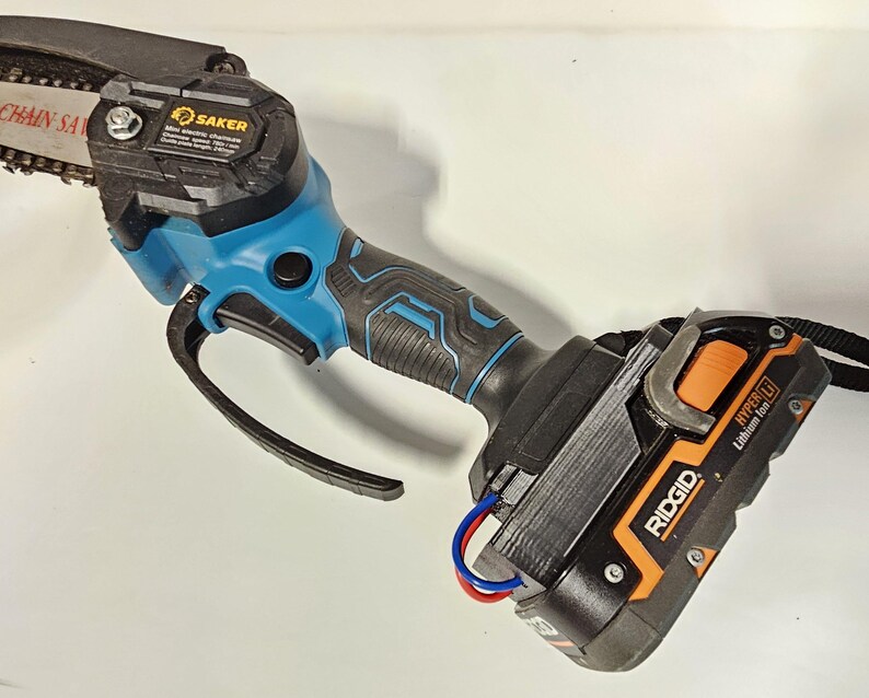 K&ouml;nnte beinhalten: Eine blaue und schwarze Akku-Kettens&auml;ge mit einem schwarzen und orangefarbenen Akku-Pack mit der Aufschrift "RIDGID HYPER LI Lithium Ion".