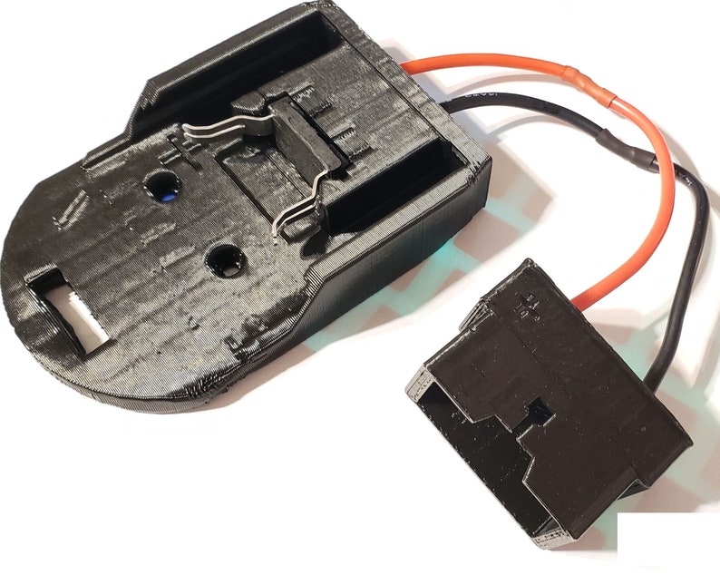 May include: A black plastic battery holder with two metal clips and a black plastic connector with red and black wires attached.