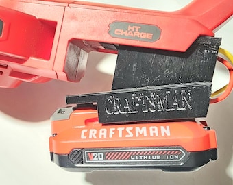 May include: A red and black Craftsman power tool with a V20 Lithium Ion battery. The tool has the text "HT CHARGE" on the side. The battery is orange and black with the Craftsman logo and "V20 Lithium Ion" printed on it.
