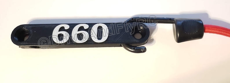 Puede incluir: Gancho de pl&aacute;stico negro con el n&uacute;mero "660" impreso en blanco. Un cord&oacute;n rojo est&aacute; unido al gancho.