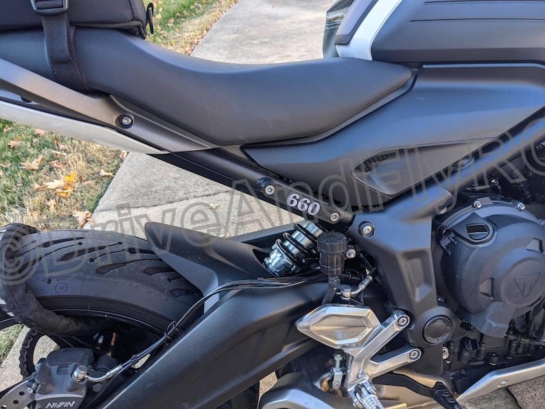 Puede incluir: Una motocicleta negra con un asiento plateado y un motor negro y plateado. La motocicleta tiene un guardabarros trasero negro con un ribete plateado y el n&uacute;mero "660" impreso en &eacute;l.