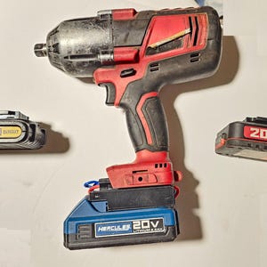 May include: A black and red impact wrench with a black handle and a silver head. Three 20V batteries are also in the image, including a black and yellow DeWalt battery, a black and red Bauer battery, and a blue Hercules battery.