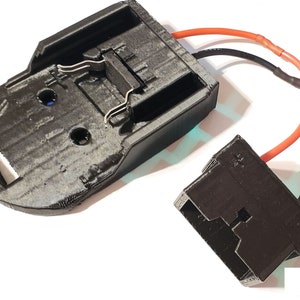 May include: A black plastic battery holder with two metal clips and a black plastic connector with red and black wires attached.