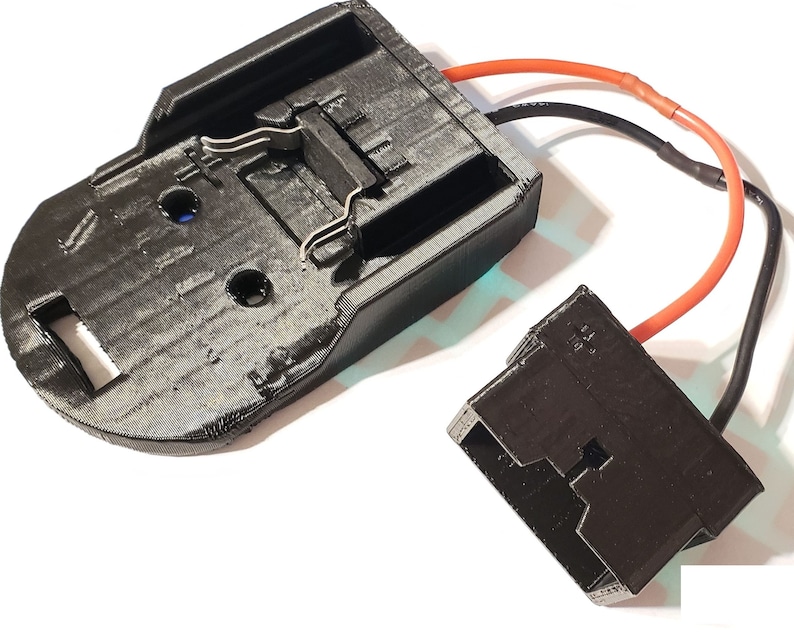 May include: A black plastic battery holder with two metal clips and a black plastic connector with red and black wires attached.