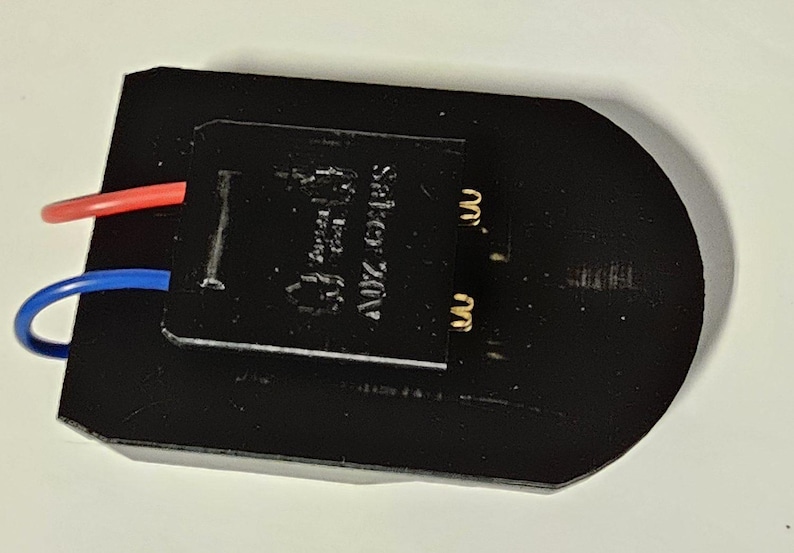K&ouml;nnte beinhalten: Schwarzes elektrisches Bauteil mit zwei Dr&auml;hten, einem roten und einem blauen, die daran befestigt sind. Das Bauteil tr&auml;gt ein Etikett mit der Aufschrift "AUTOMATIC SWITCH".