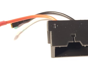 May include: A black electrical connector with three wires attached. The wires are red, white, and black. The connector has a rectangular shape with a slot on the top.