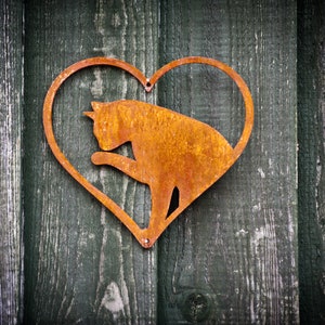 May include: A rusty metal heart-shaped silhouette of a cat on a wooden background.