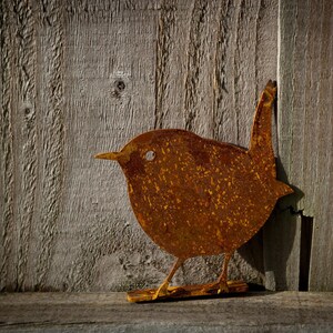 Metal wren silhouette on a wooden fence, highlighting its compact form and rich, earthy tones. Precision-cut from sturdy steel for long-lasting outdoor use, this rustic bird accent elevates a fence, fence post, tree, arbour, pergola, shed or wall.