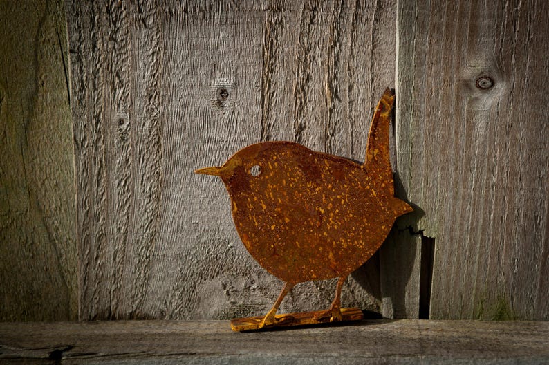 Metal wren silhouette on a wooden fence, highlighting its compact form and rich, earthy tones. Precision-cut from sturdy steel for long-lasting outdoor use, this rustic bird accent elevates a fence, fence post, tree, arbour, pergola, shed or wall.