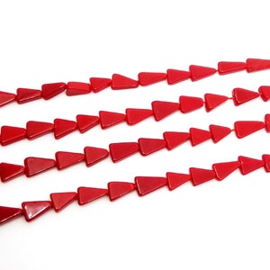 May include: A strand of red triangle-shaped beads. The beads are made of glass and have a glossy finish.