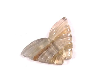 May include: A carved butterfly pendant made of translucent light brown and white gemstone. The wings are detailed with intricate carvings.