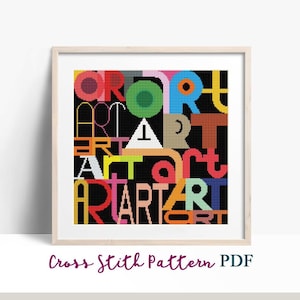May include: Cross stitch pattern featuring the word "ART" repeated in various colors and fonts on a black background. The pattern is framed in a light wood frame.