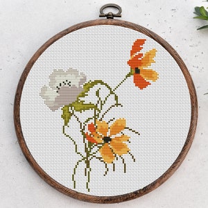 May include: A cross-stitch embroidery hoop with a floral design. The design features three flowers in shades of orange, yellow, and white.
