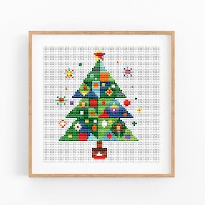 May include: A cross-stitch pattern of a Christmas tree in a light wood frame. The tree is composed of green, blue, red, and yellow geometric shapes with a star on top. Small colorful snowflake-like motifs surround the tree on a white fabric.