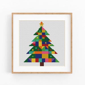 May include: A framed cross-stitch artwork featuring a stylized Christmas tree composed of a patchwork of vibrant, multi-colored squares in shades of green, blue, yellow, red, and pink, topped with a small yellow star and a brown trunk.