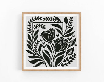 May include: Black and white cross-stitch pattern featuring a floral design with two large flowers and leaves in a square frame.