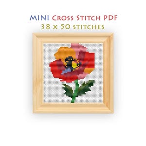 May include: A cross stitch pattern in a light wood frame featuring a red, orange, and pink flower with a green stem on a white grid. The text above reads MINI CROSS STITCH PDF 38 x 50 STITCHES. The design uses a pixelated style for the floral motif.
