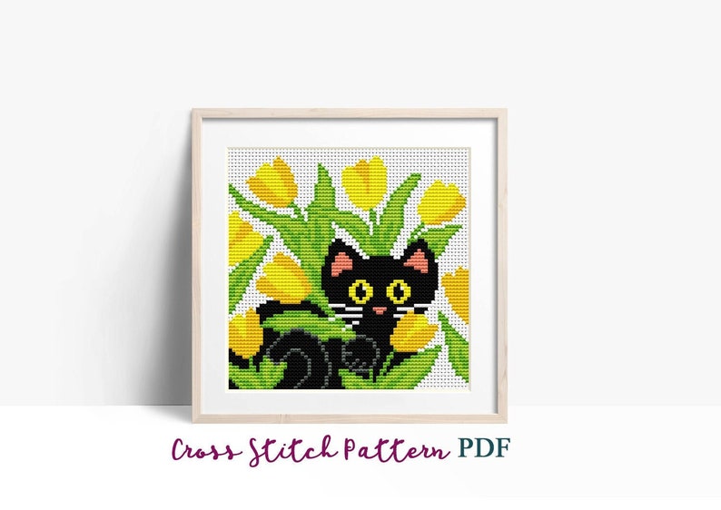 K&ouml;nnte beinhalten: Kreuzstichmuster mit einer schwarzen Katze mit gelben Augen, die hinter einem Strau&szlig; gelber Tulpen mit gr&uuml;nen Bl&auml;ttern hervorlugt.