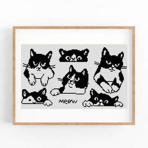 May include: A framed print featuring a collection of black and white cat illustrations. The cats have various poses and expressions, with the word "MEOW" included. The artwork is in a pixelated style, giving it a unique, handcrafted appearance.