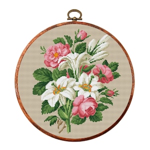 May include: A cross-stitch embroidery hoop with a floral design featuring white lilies and pink roses on a beige background.