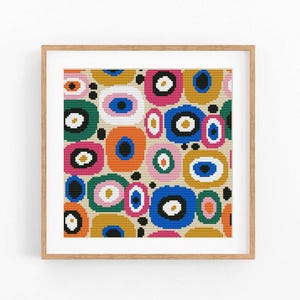 May include: A framed print featuring a colorful abstract design. The artwork showcases a pattern of overlapping oval and circular shapes in various colors, including pink, blue, orange, and green, set against a beige background. The frame is made of light-colored wood.