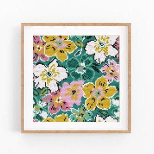 Puede incluir: Una impresión floral enmarcada con un patrón repetido de flores estilizadas. Las flores son en tonos de amarillo, rosa y blanco, sobre un fondo verde turquesa. La obra de arte se muestra en un marco de madera marrón claro.
