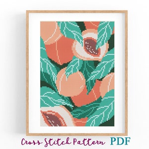 May include: Cross-stitch pattern of peaches and leaves in a framed print. The design features ripe peaches in shades of orange and pink, surrounded by green leaves. The text "Cross Stitch Pattern PDF" is at the bottom.
