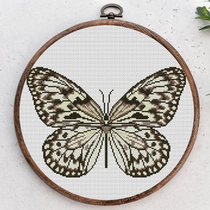 May include: A white and brown butterfly cross-stitch pattern in a wooden embroidery hoop.