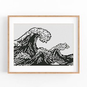 May include: A framed cross-stitch pattern featuring a black and white pixelated design of a large ocean wave. The artwork is displayed within a light-colored wooden frame, showcasing a detailed grid-like composition of the crashing sea.