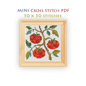 May include: A framed cross stitch pattern featuring three red tomatoes on a brown vine with green leaves against a white background. The text above reads MINI CROSS STITCH PDF 50 x 50 STITCHES. The design is displayed in a light wood frame.