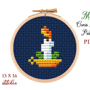 Puede incluir: Un patrón de punto de cruz en PDF para una vela sobre un fondo azul. El patrón tiene 13 puntos de ancho por 16 puntos de alto.