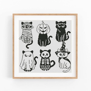 May include: A square cross-stitch pattern featuring six black and white pixelated cats dressed in Halloween costumes, including a mummy, a pumpkin head, a Frankenstein monster, a ghost, a skeleton, and a cat wearing a witch hat and cape.