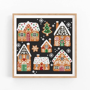 May include: A cross-stitch pattern featuring a gingerbread village with seven gingerbread houses, a Christmas tree, and snowflakes on a black background.