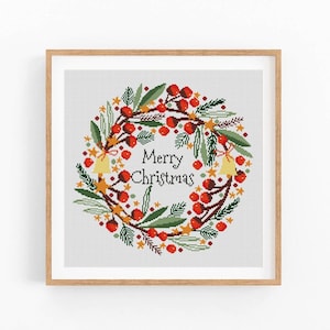 Peut inclure: Un motif de point de croix représentant une couronne de Noël avec des baies rouges, des feuilles vertes et des étoiles dorées. La couronne porte l'inscription "Merry Christmas" au centre.