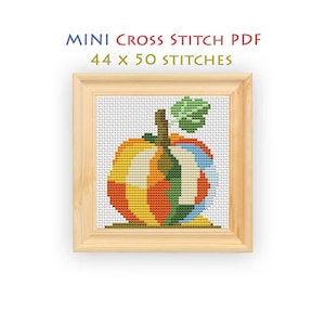 May include: A cross stitch pattern featuring a pumpkin with a green leaf, displayed in a light wood frame. The text above reads MINI CROSS STITCH PDF 44 x 50 STITCHES. The pumpkin is composed of vertical segments in orange, yellow, blue, and green.