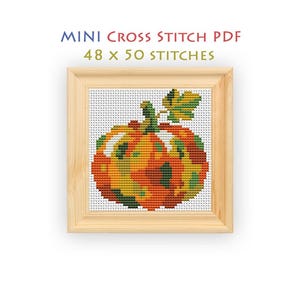 May include: A mini cross stitch PDF pattern featuring a pumpkin design with orange, yellow, and green colors. The text reads MINI CROSS STITCH PDF 48 x 50 STITCHES. The design is displayed within a light-colored wooden square frame.