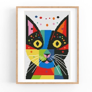 Może przedstawiać: Kolorowy, abstrakcyjny wzór haftu krzyżykowego przedstawiający twarz kota. Futro kota jest patchworkiem jasnych kolorów, w tym czerwonego, żółtego, zielonego, niebieskiego i czarnego. Oczy kota są duże i czarne z żółtymi źrenicami. Tło jest białe z małymi, kolorowymi kropkami.