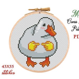 Pode incluir: Um padrão de ponto cruz de um pato de desenho animado em um bastidor de bordado de madeira. O pato é branco com bico e pés amarelos, e detalhes amarelos nas asas. O texto "Mini Cross Stitch Pattern PDF" está no canto superior direito. O padrão tem 43x55 pontos.