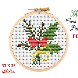 May include: A cross stitch pattern for a small Christmas holly design with red berries and a yellow bow. The pattern is 33 stitches by 33 stitches. The pattern is in a wooden embroidery hoop.